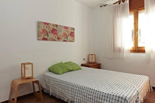 a bedroom with a bed with a green pillow on it at Apartamento Pau Casals in L'Ametlla de Mar