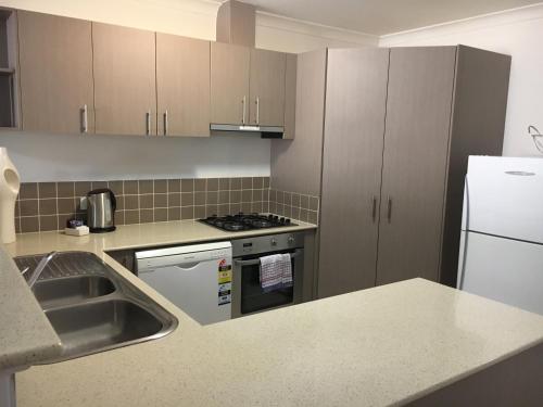 una cocina con fregadero y estufa horno superior en Geographe Bay Apartment, en Busselton