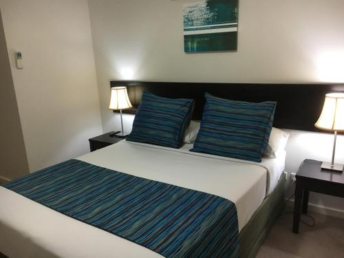 a bedroom with a bed with blue pillows and two lamps at Geographe Bay Apartment in Busselton
