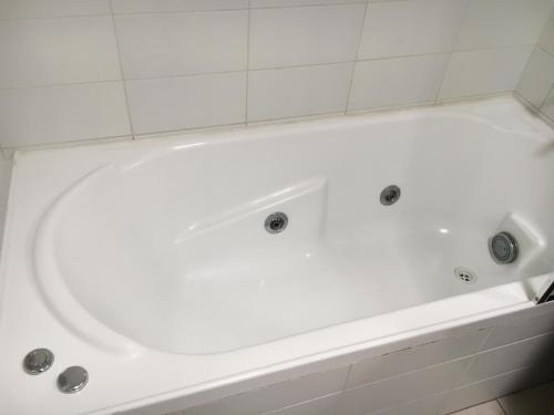 bañera blanca con 2 grifos en el baño en Geographe Bay Apartment, en Busselton