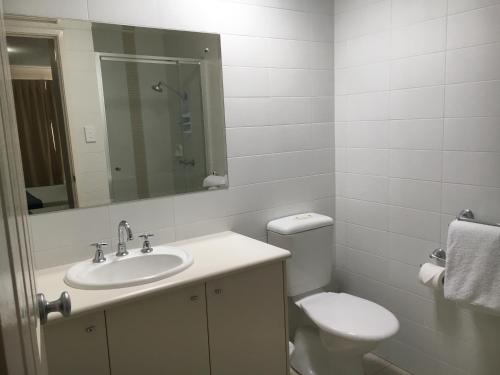 Un baño con lavabo, inodoro y espejo. en Geographe Bay Apartment, en Busselton