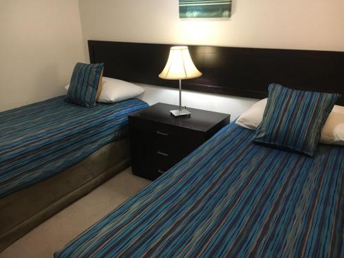 Una habitación de hotel con dos camas y una lámpara. en Geographe Bay Apartment, en Busselton