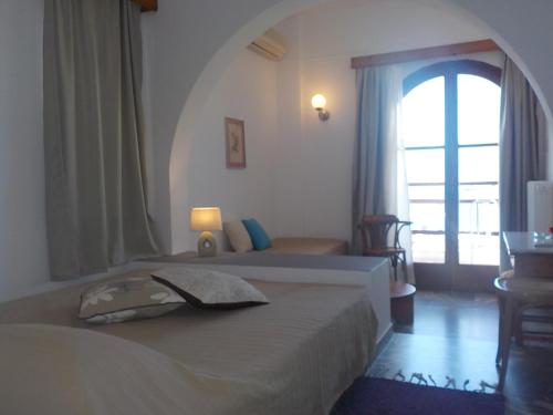 a bedroom with a bed with a large window at Dilina Guesthouse in Agios Nikolaos