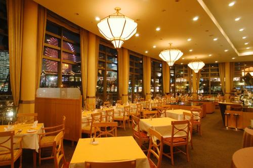un restaurante con mesas, sillas y lámparas de araña en Navios Yokohama en Yokohama