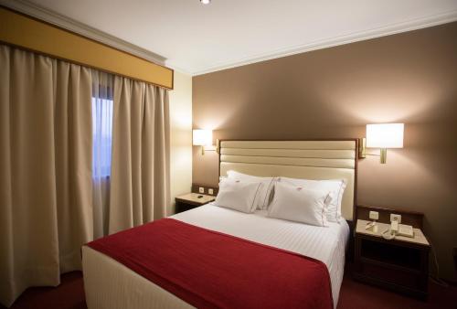 a hotel room with a bed with a red blanket at Hotel Miracorgo in Vila Real