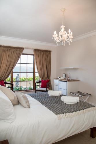 a bedroom with a large white bed with a chandelier at Moncrieff Manor in Knysna