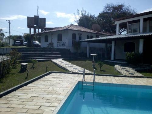 uma casa com piscina em frente a uma casa em Pousada Tourne Bride em Araruama