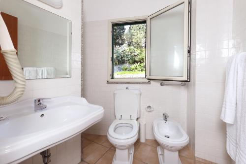 a bathroom with a toilet, sink and tub at Hotel Villino Gallodoro in Taormina