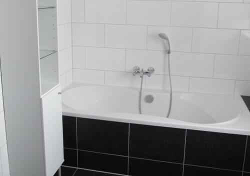 y baño con bañera blanca y ducha. en Vakantiehuizen Hofstede Elzenoord, en Vrouwenpolder