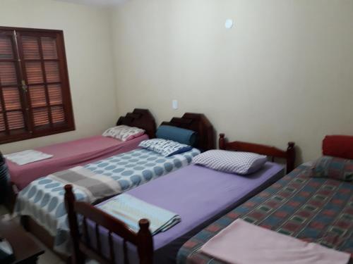 um quarto com três camas e uma janela em Lindo Apartamento praia e quiosque abertos em Cabo Frio