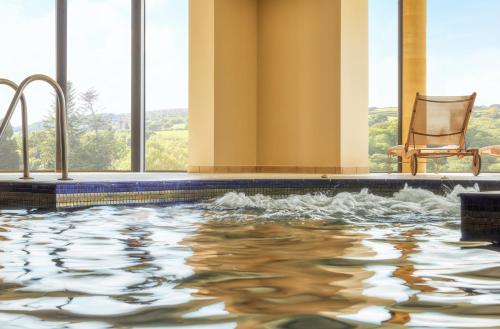 a swimming pool with a chair in a building at Bovey Castle in Moretonhampstead