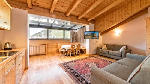 a kitchen and living room with a couch and a table at Residence Cesa Rives in Selva di Val Gardena