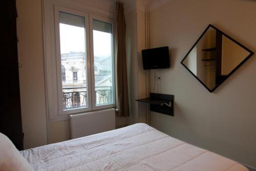 a bedroom with a bed and a window at Hotel De Londres in Lille