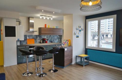 une cuisine avec un comptoir et des tabourets dans une pièce dans l'établissement Appartement à 2min du plan d'eau, à Vichy