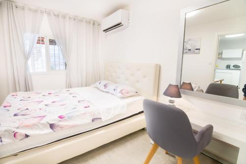 1 dormitorio con cama, espejo y silla en Asher's Apartments, en Eilat
