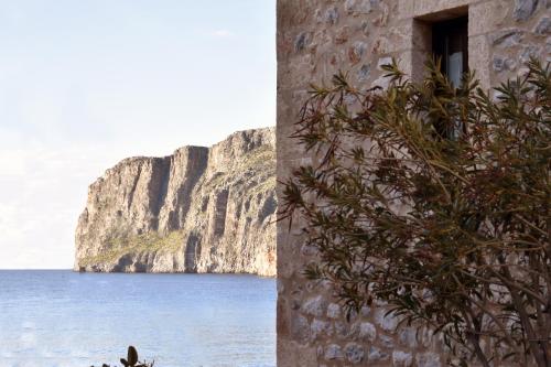 a building with a tree next to a body of water at Pyrgoi Theodorakaki: O Gerolimenas in Gerolimenas