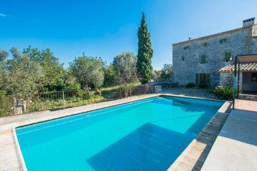 a swimming pool in front of a house with a building at Can Guillo in Pollença