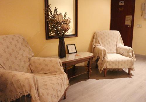 a room with two chairs and a table and a vase with flowers at Pensión San Isidro in Madrid