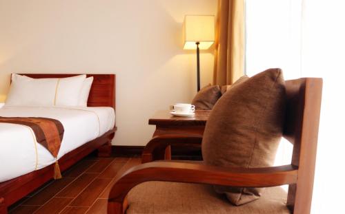a bedroom with a bed and a chair and a table at Chang Palace Vientiane in Vientiane