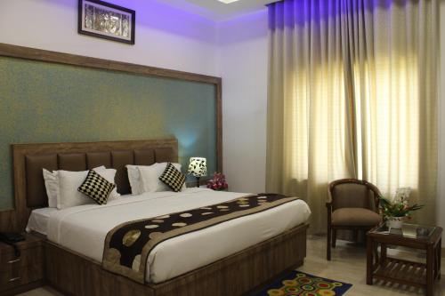 a bedroom with a large bed and a chair at Regal Hotel and restaurant in Mathura