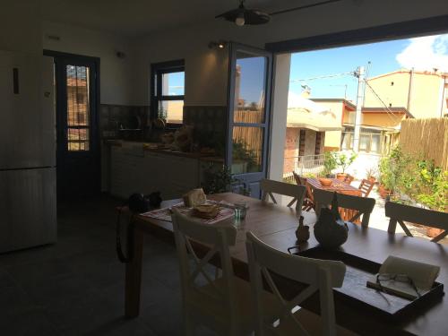 a dining room table with chairs and a kitchen with a window at B&B Francisca in Tortolì