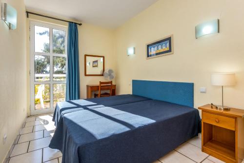 een slaapkamer met een blauw bed en een raam bij Club Ouratlantico in Albufeira