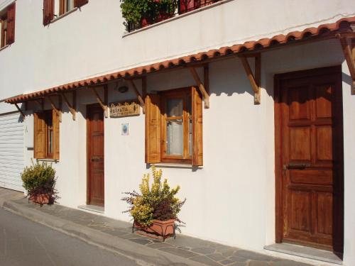 a white building with wooden doors and potted plants at Zephyros in Vytina