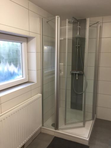 a glass shower in a bathroom with a window at Ferienhaus Kluntje in Emden