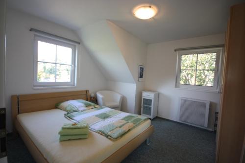 a small bedroom with a bed and two windows at Ferienpark An der Seebrücke in Ostseebad Koserow