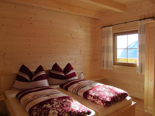 two beds in a log cabin with a window at Ebner Casa in Heiligenblut