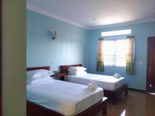 two beds in a room with blue walls and a window at Siem Reap home in Siem Reap