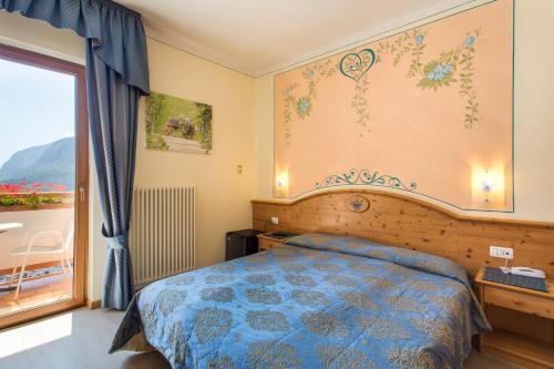 a bedroom with a bed and a large window at Hotel Florida in Molveno