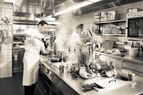 two chefs preparing food in a commercial kitchen at Hotel Le Grand Chalet Gstaad in Gstaad