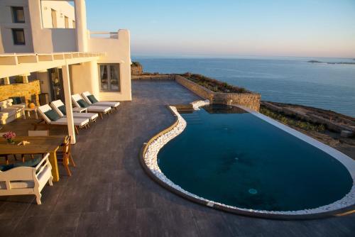 a swimming pool next to a building with the ocean at Naxos Rock Villas in Stelida