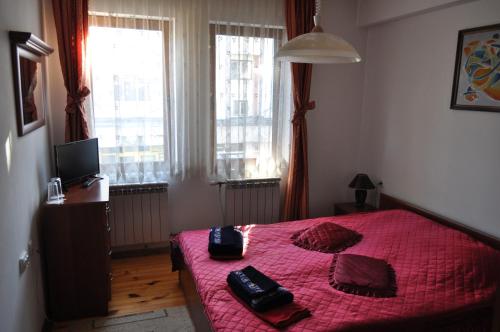 a bedroom with a red bed with two phones on it at Guest Rooms Biju in Tryavna