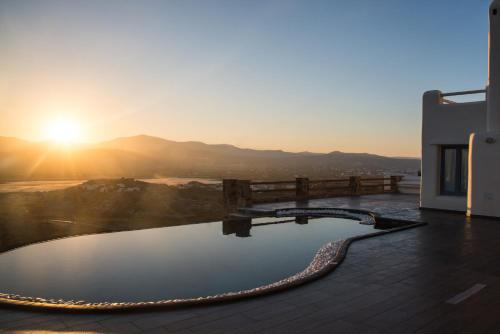 a pool on the roof of a house with the sunset at Naxos Rock Villas in Stelida