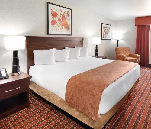 a hotel room with a large bed and a chair at Crystal Inn Hotel & Suites - Salt Lake City in Salt Lake City