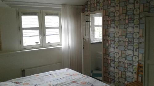 een slaapkamer met een bed en twee ramen en een gordijn bij Holiday home Jong in Schagerbrug