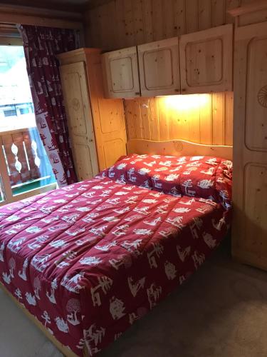 une chambre avec un lit avec une couverture rouge dans l'établissement Le Tremplin, à Méribel