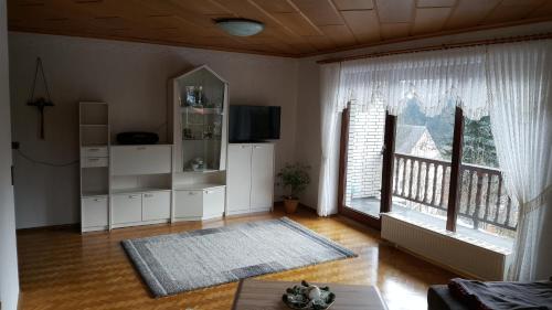 a living room with a television and two large windows at Haus Vor den Eichen für Familien in Willingen