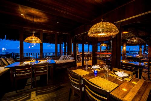 a restaurant with wooden tables and chairs and chandeliers at Hotel Sombra e Água Fresca in Pipa