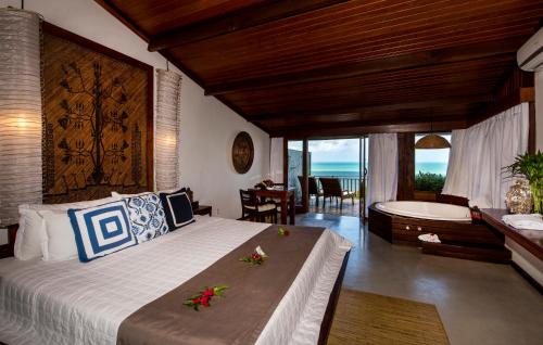 a bedroom with a bed and a bathroom with a tub at Hotel Sombra e Água Fresca in Pipa