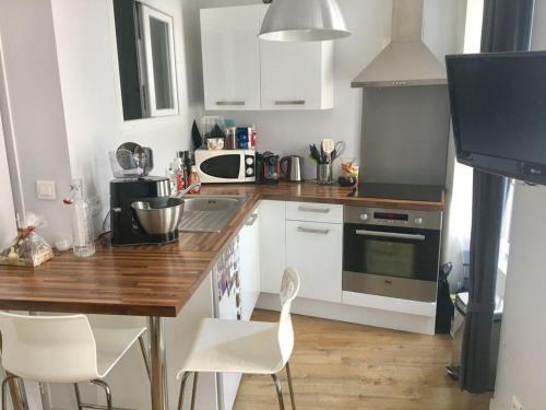 une cuisine avec des armoires blanches et un comptoir en bois dans l'établissement Appt 2 à 4 pers - La Rochelle Vieux Port, à La Rochelle