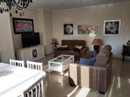 a living room with a couch and a tv at GEMELOS 26 APARTMENTS - Benidormland in Benidorm