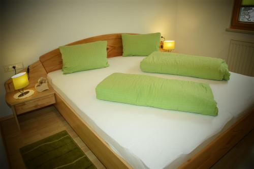 ein großes Bett mit zwei grünen Kissen darauf in der Unterkunft Apart Dominika in Ried im Oberinntal