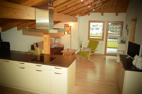 a kitchen with white cabinets and a living room at Apart Dominika in Ried im Oberinntal