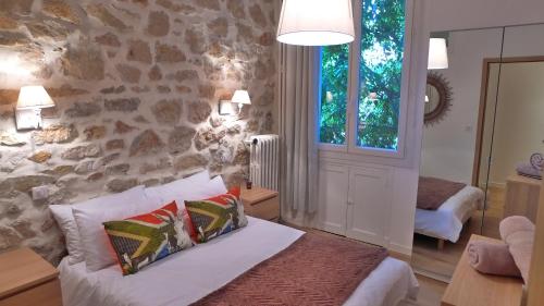 ein Schlafzimmer mit einem Bett und einer Steinmauer in der Unterkunft Stylish two-bedroom apartment -StayInAntibes - 5 Soleau in Antibes