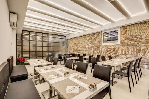un restaurant avec des tables et des chaises et un mur en briques dans l'établissement The Liberty Boutique Hotel, à Rome