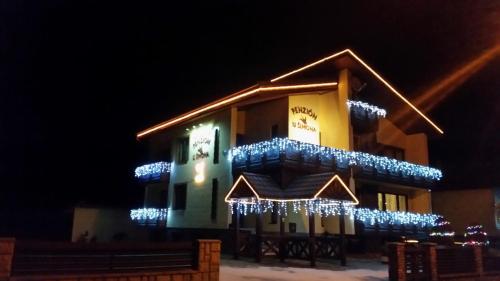 a building with christmas lights on it at night at Penzion u Šimona in Vernár