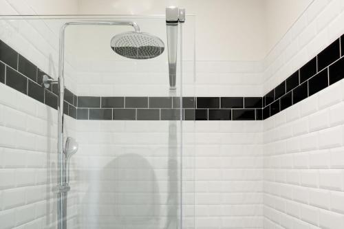 y baño con ducha y azulejos blancos y negros. en Le Clos Labottière - B&B en Burdeos